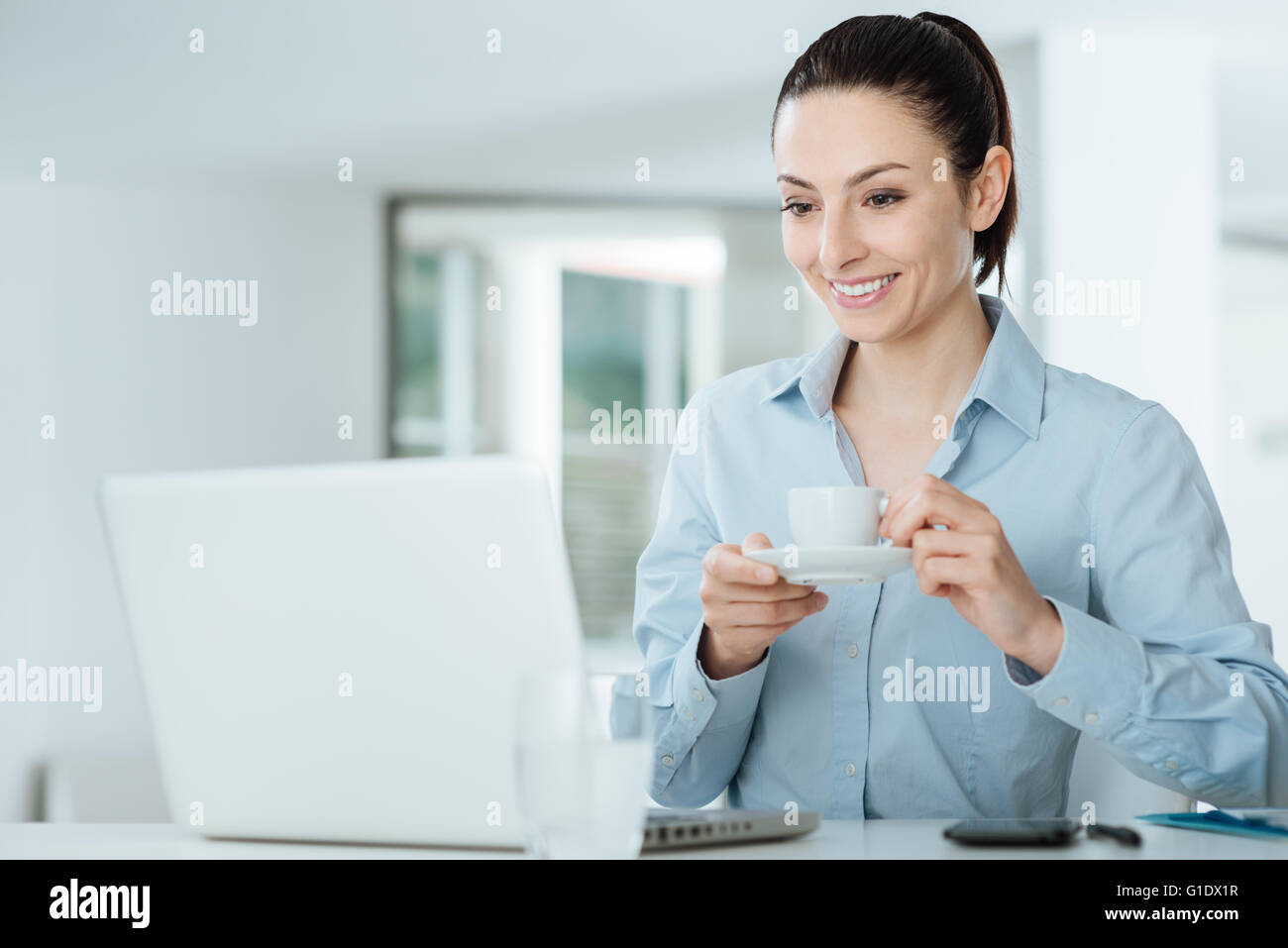 Femme regardant une vidéo sur son ordinateur portable pendant une pause-café Banque D'Images