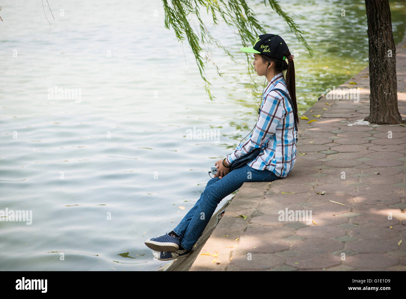 Jeune fille vietnamienne assis par un lac, Hanoi Banque D'Images