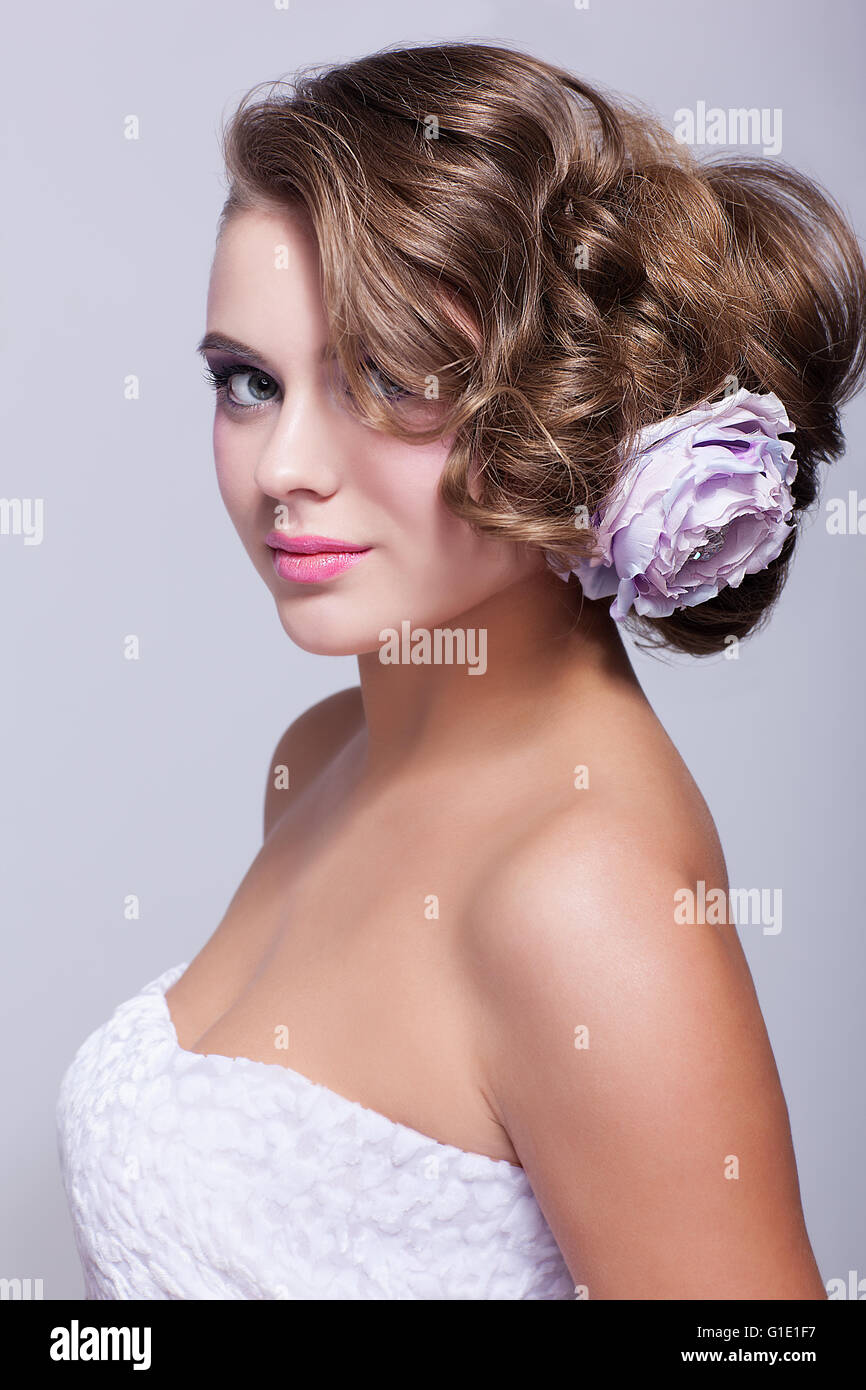 Portrait de la belle jeune femme sur fond gris avec des poils en fleur pion Banque D'Images