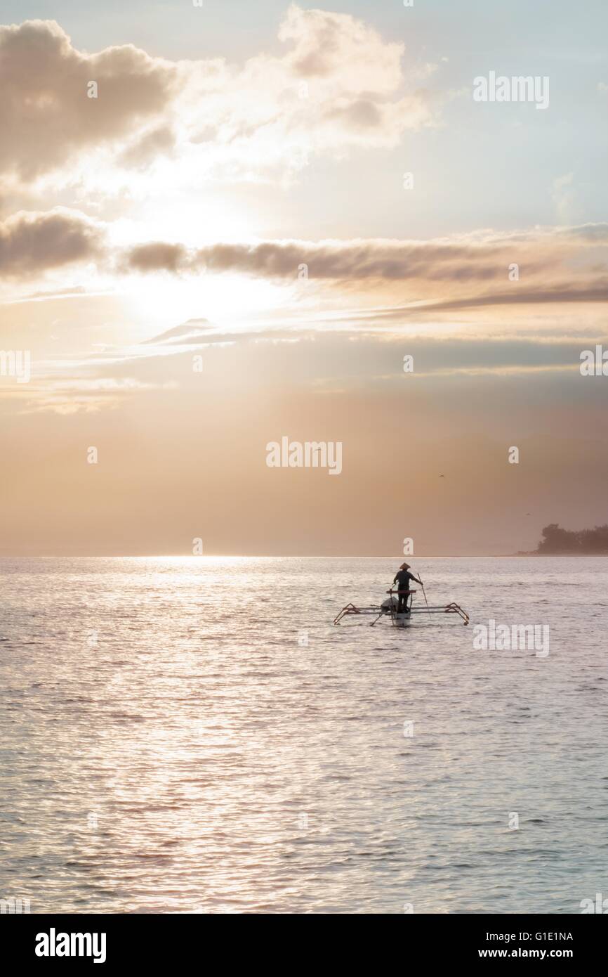 Pêcheur indonésien au large a va avec son conique en catamaran sunrise rose Banque D'Images