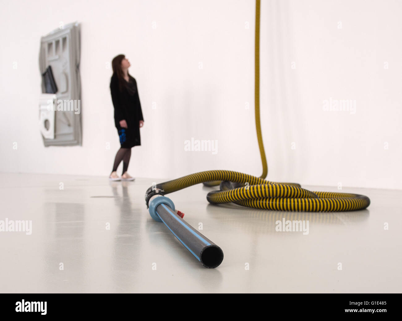 Hambourg, Allemagne. 13 mai, 2016. Une femme regarde une oeuvre faite d'un flexible d'extraction lors d'une exposition par l'artiste Andreas Slominski au hall d'exposition Deichtorhallen de Hambourg (Allemagne), 13 mai 2016. Slominksi a créé une installation artistique faite de plus de 100 toilettes portables. Photo : Daniel Bockwoldt/dpa/Alamy Live News Banque D'Images