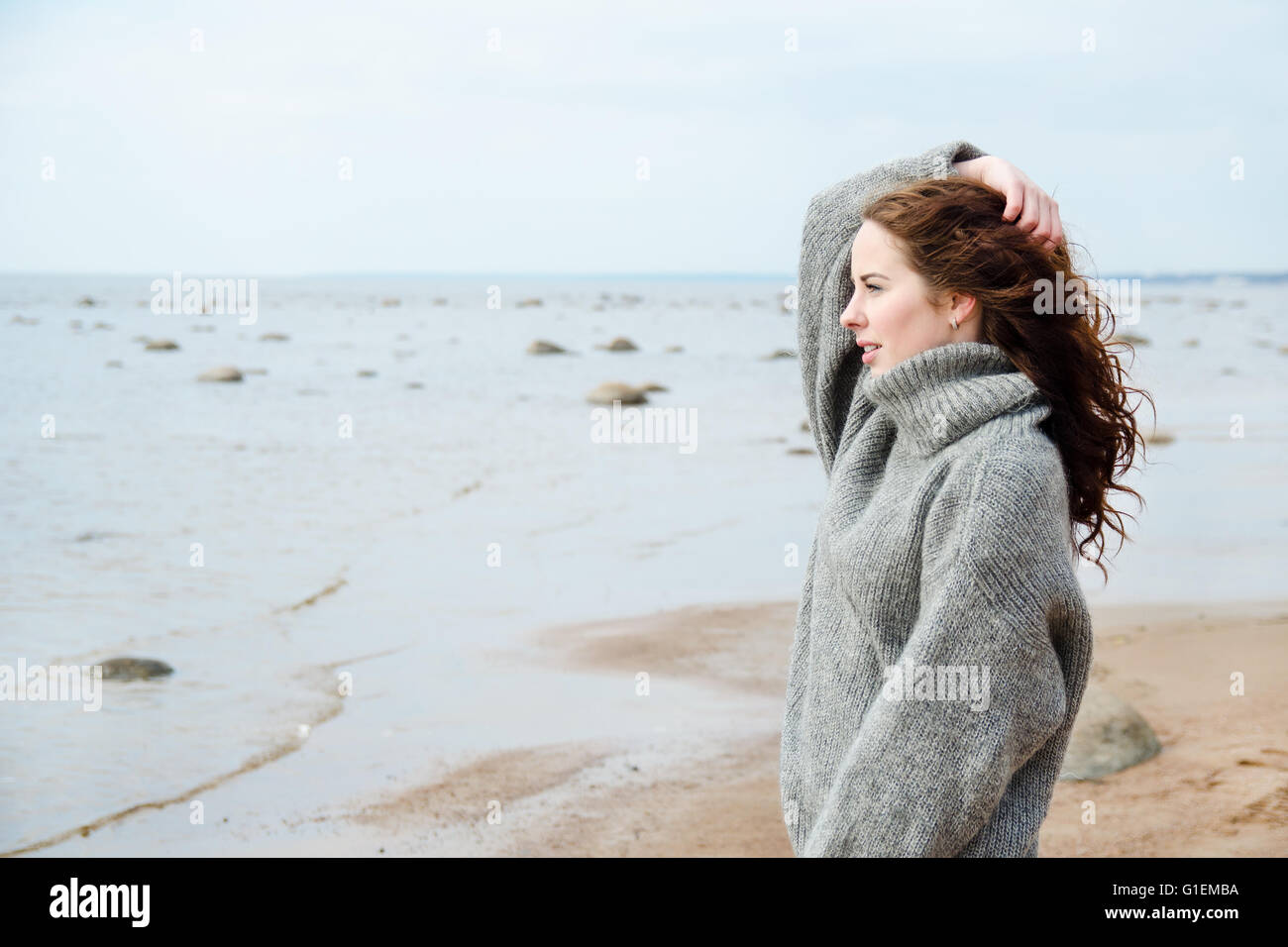 Jolie femme portant un cardigan chaud froid à la plage Banque D'Images