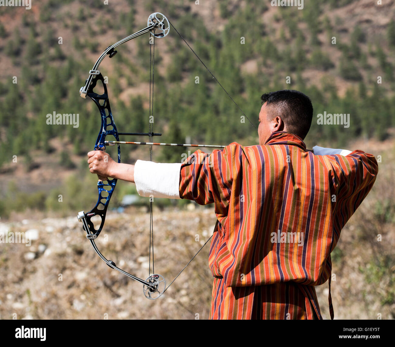 Archer vêtu du costume traditionnel robe bhoutanais practicing archery (sport national) dans la campagne Bhoutan Banque D'Images