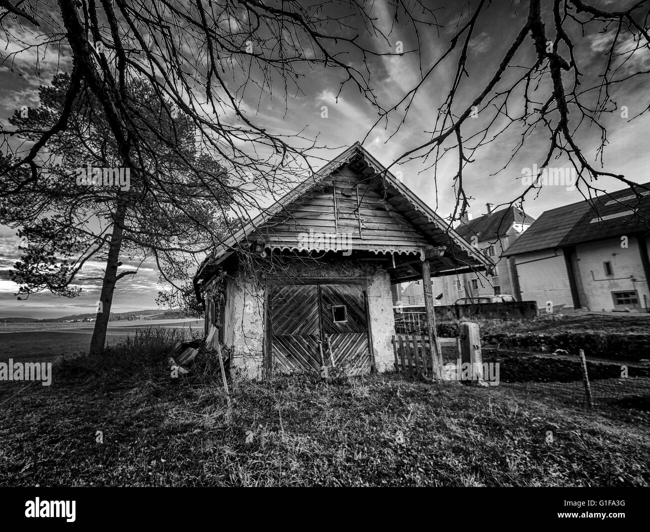Petite maison entourée d'arbres dans la campagne en noir et blanc Banque D'Images