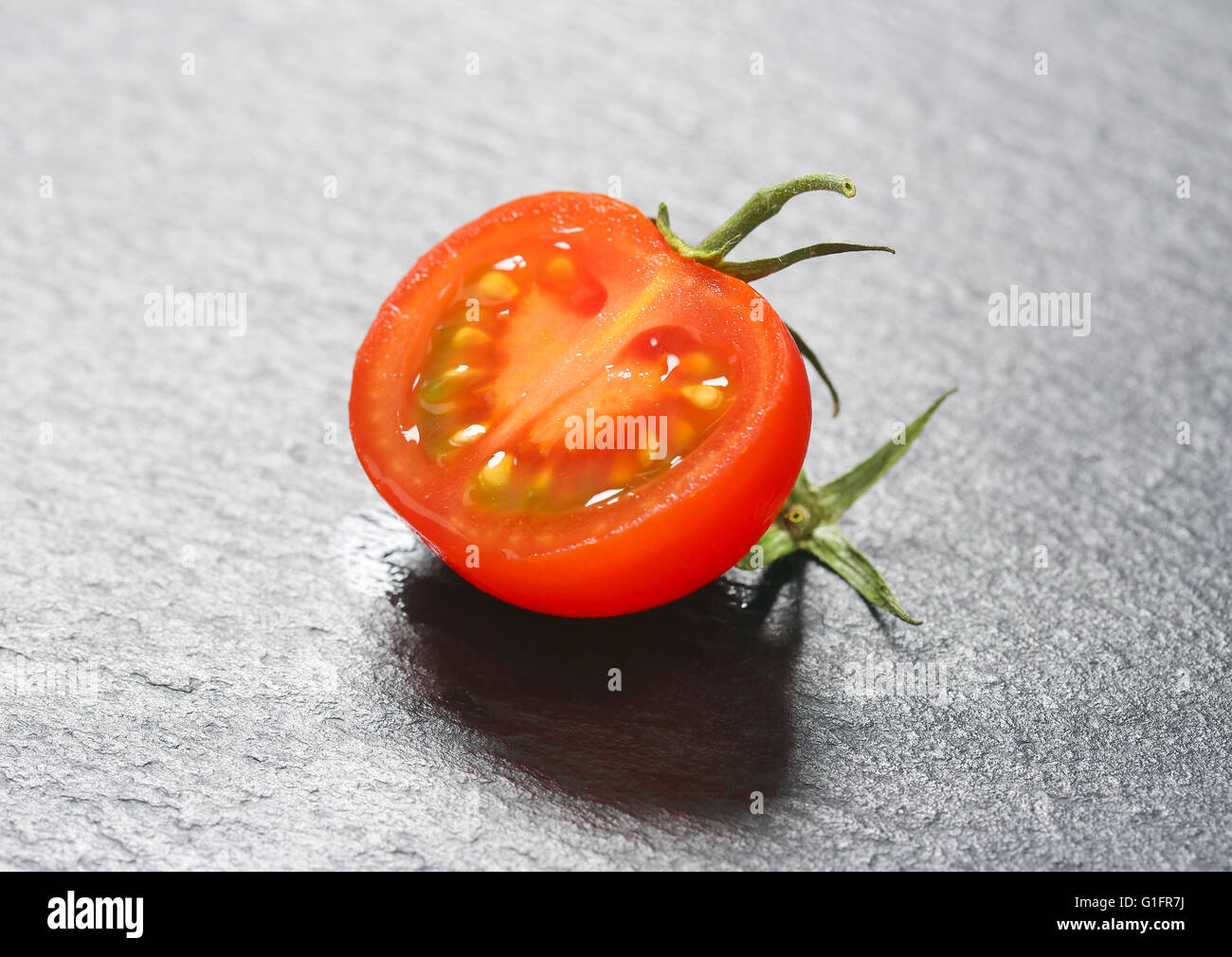 La moitié d'une tomate rouge sur ardoise Banque D'Images