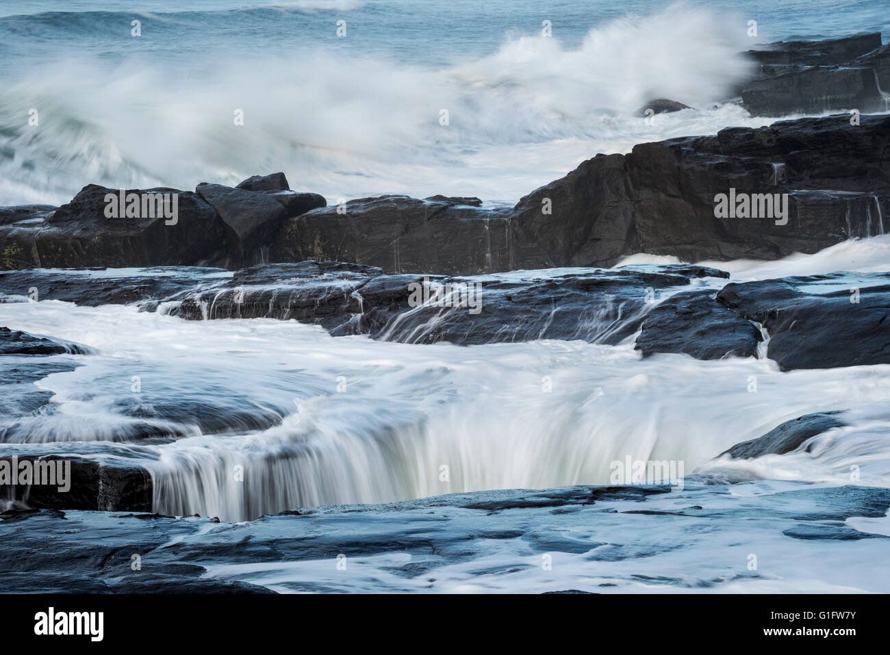 La flambée des vagues sur la pierre de lave au centre de l'Orégon Yachats sur la côte. Banque D'Images