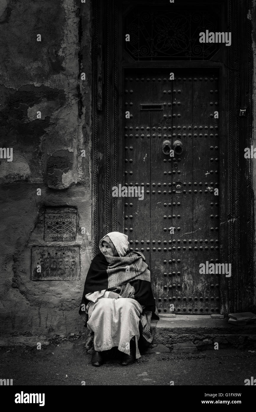 Femme assise par porte, Fès, Fès médina, Maroc Banque D'Images