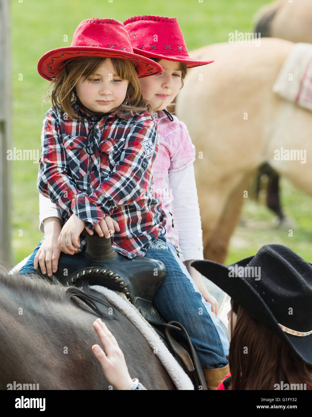 MITROV. REP tchèque - 7 mai 2016 : Deux cute little Girl with red hat à cheval sur le ranch. Banque D'Images