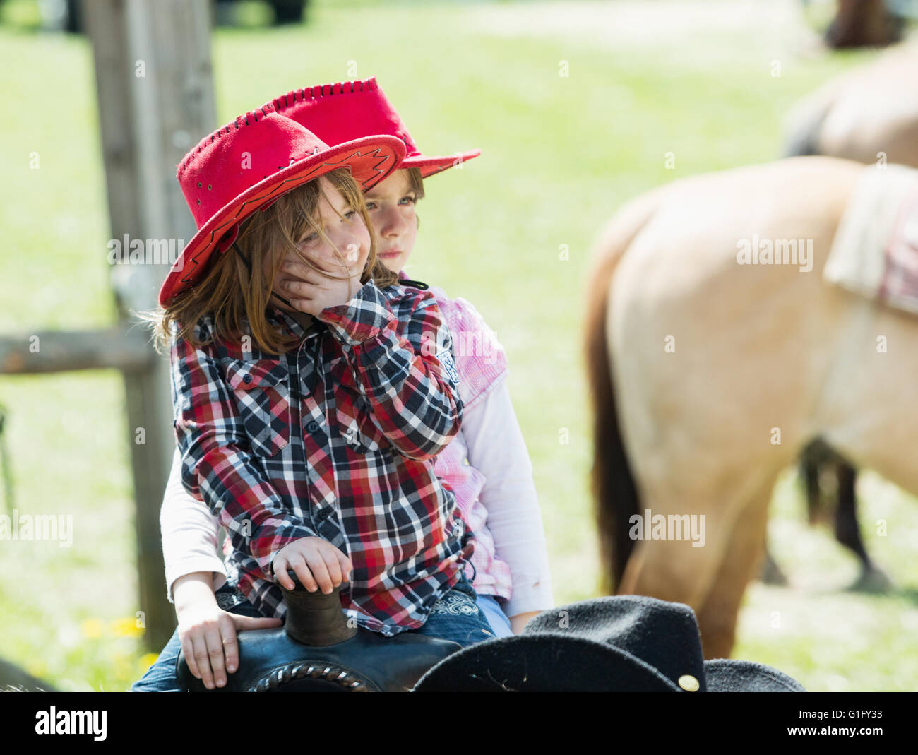 MITROV. REP tchèque - 7 mai 2016 : Deux cute little Girl with red hat à cheval sur le ranch. Banque D'Images