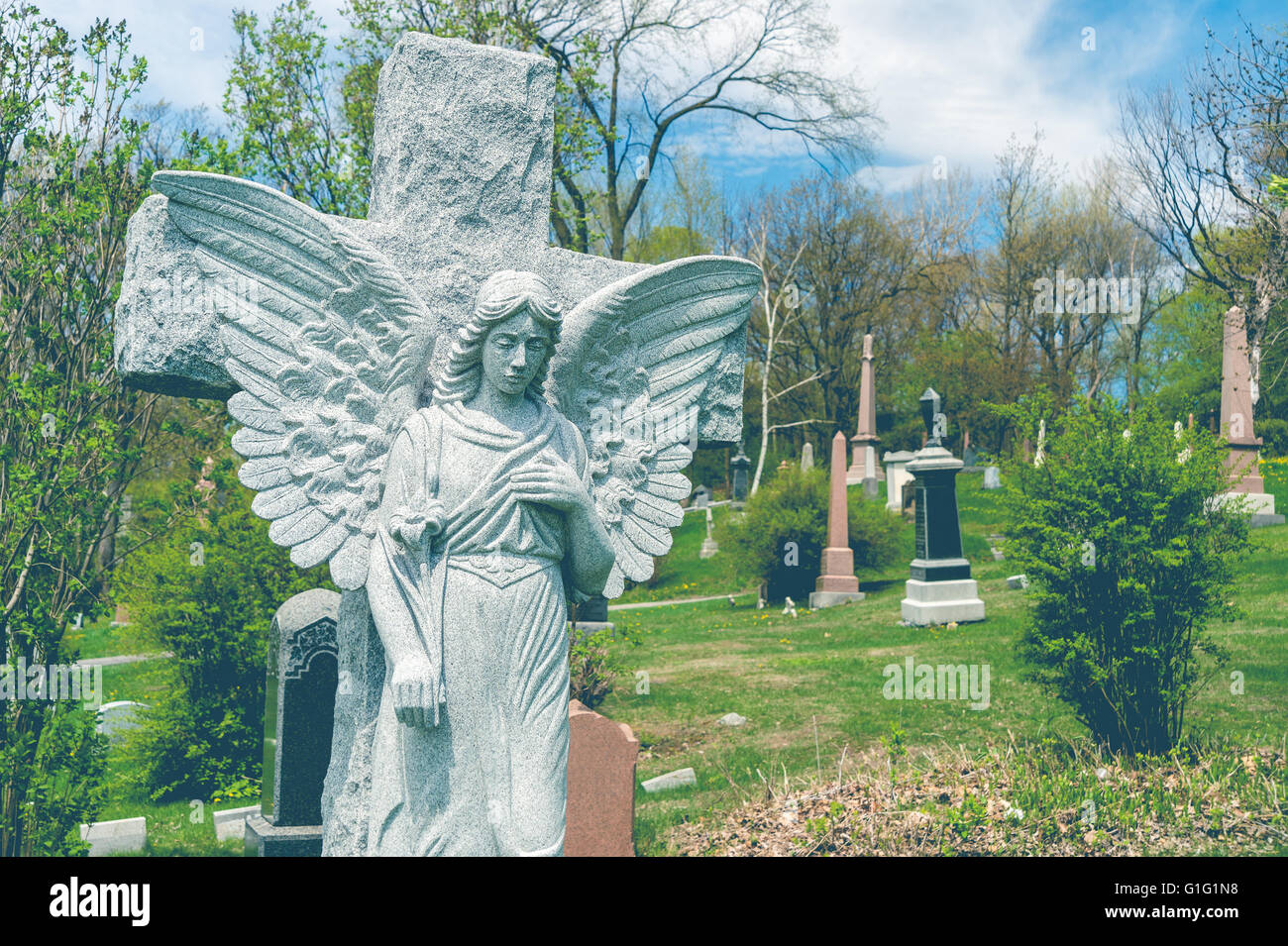 Ange devant une statue dans un cimetière, avec un effet vintage. Banque D'Images
