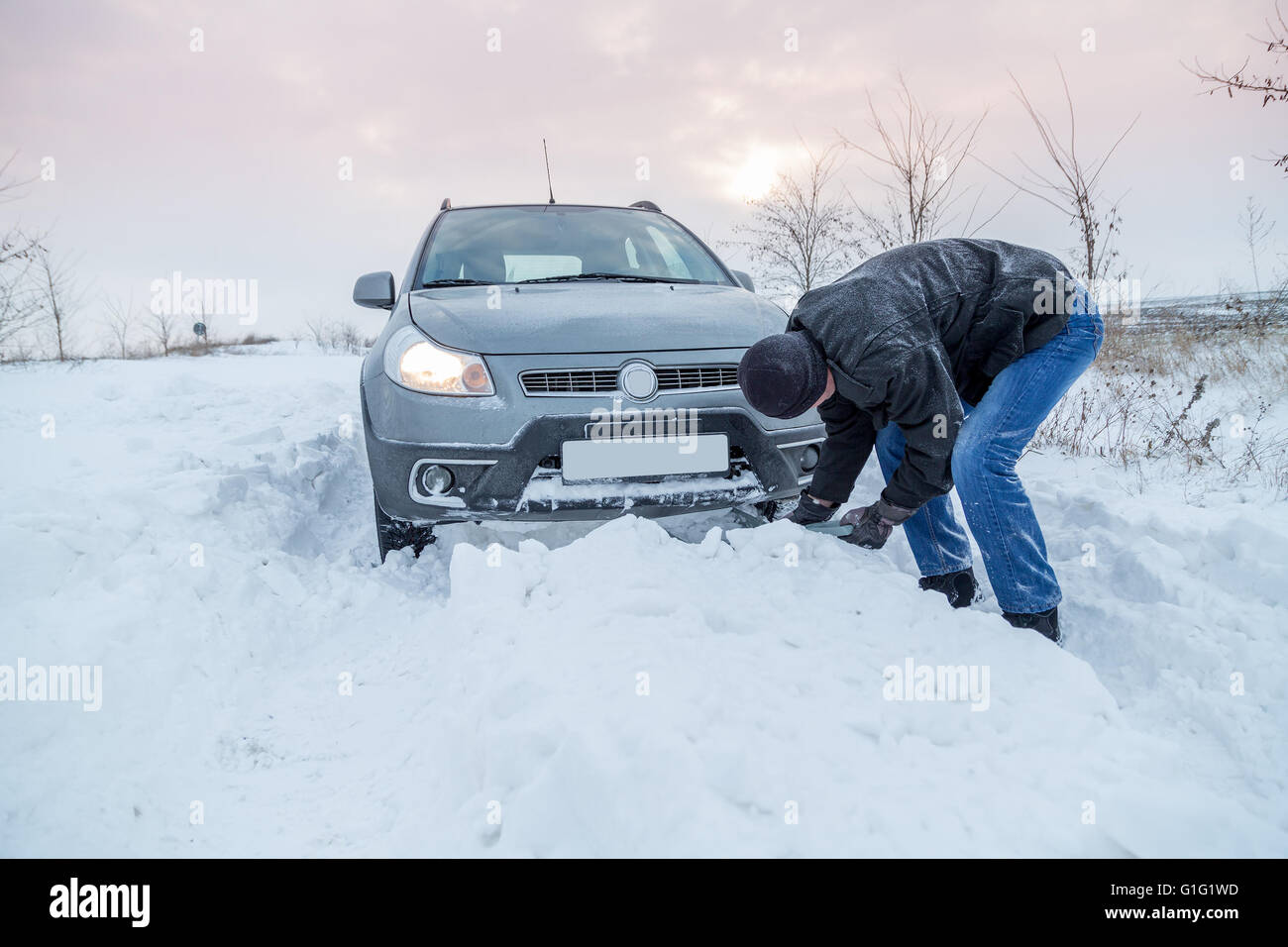 Homme de pelleter de la neige pour libérer sa voiture coincé Banque D'Images