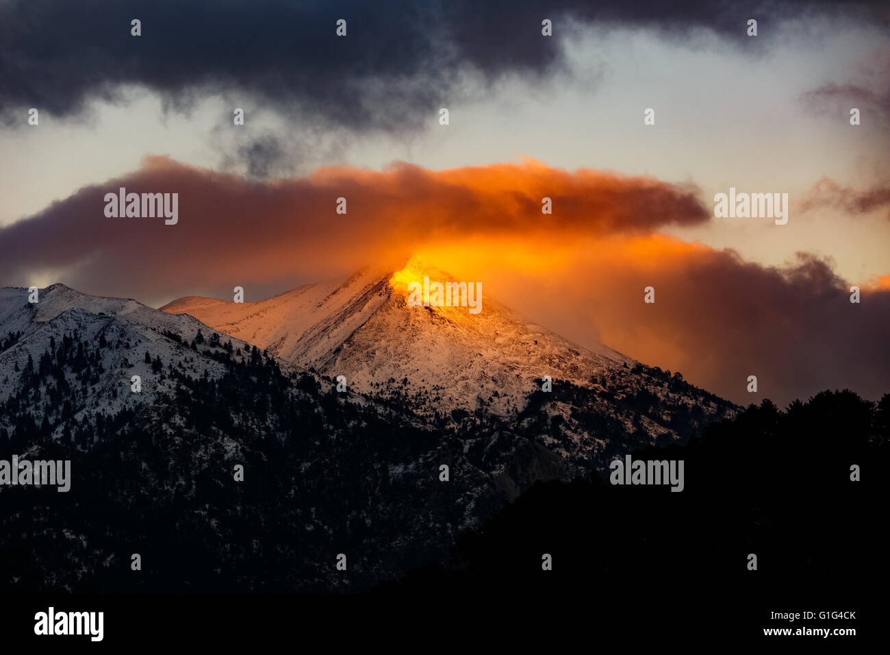 Paysage de montagne d'hiver à l'aube ou au coucher du soleil avec des rayons de lumière dorée du soleil sur le pic de production en Grèce Banque D'Images