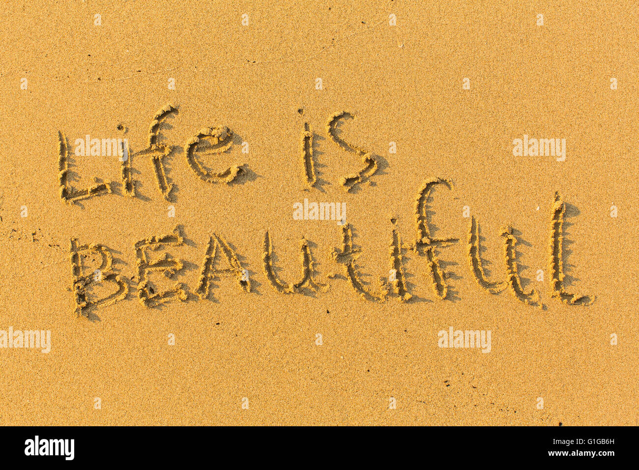La vie est belle - texte écrit sur une plage de sable. Banque D'Images