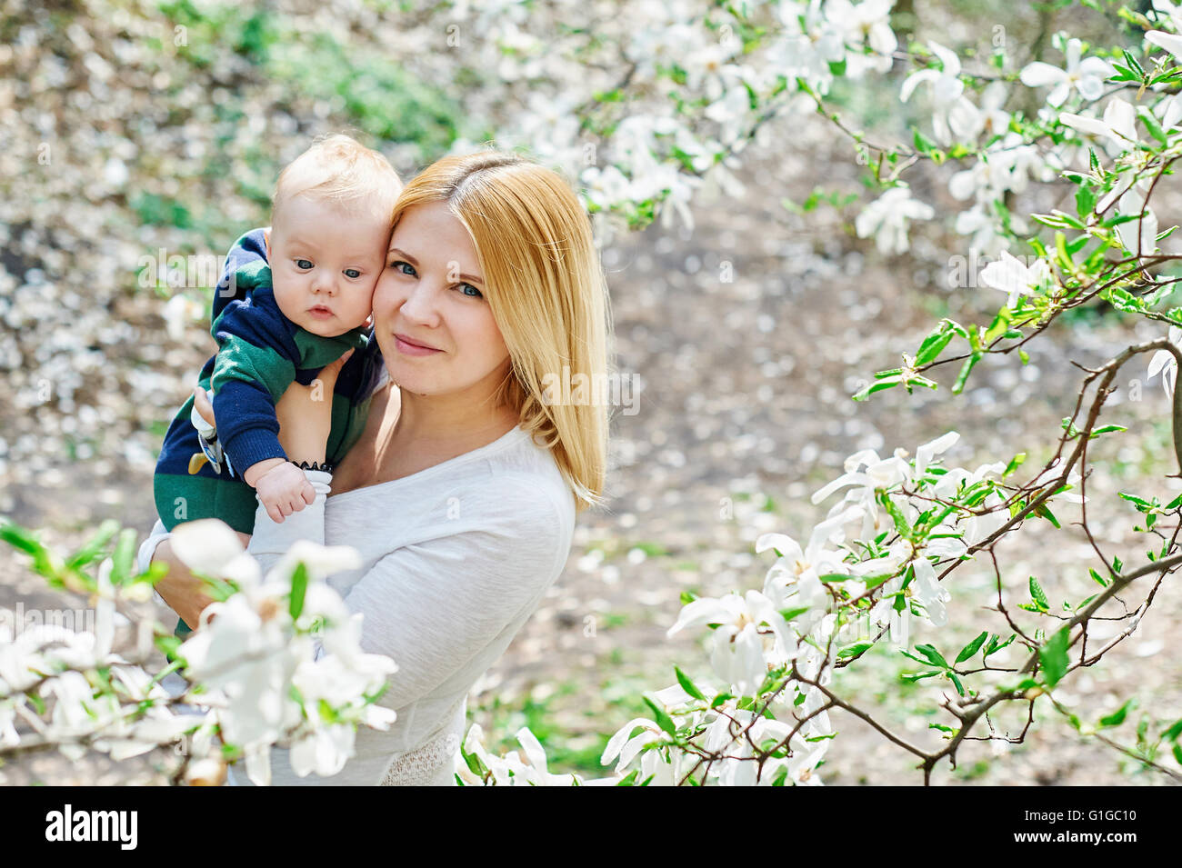 La marche de la mère avec son bébé dans son jardin de fleurs de magnolias Banque D'Images