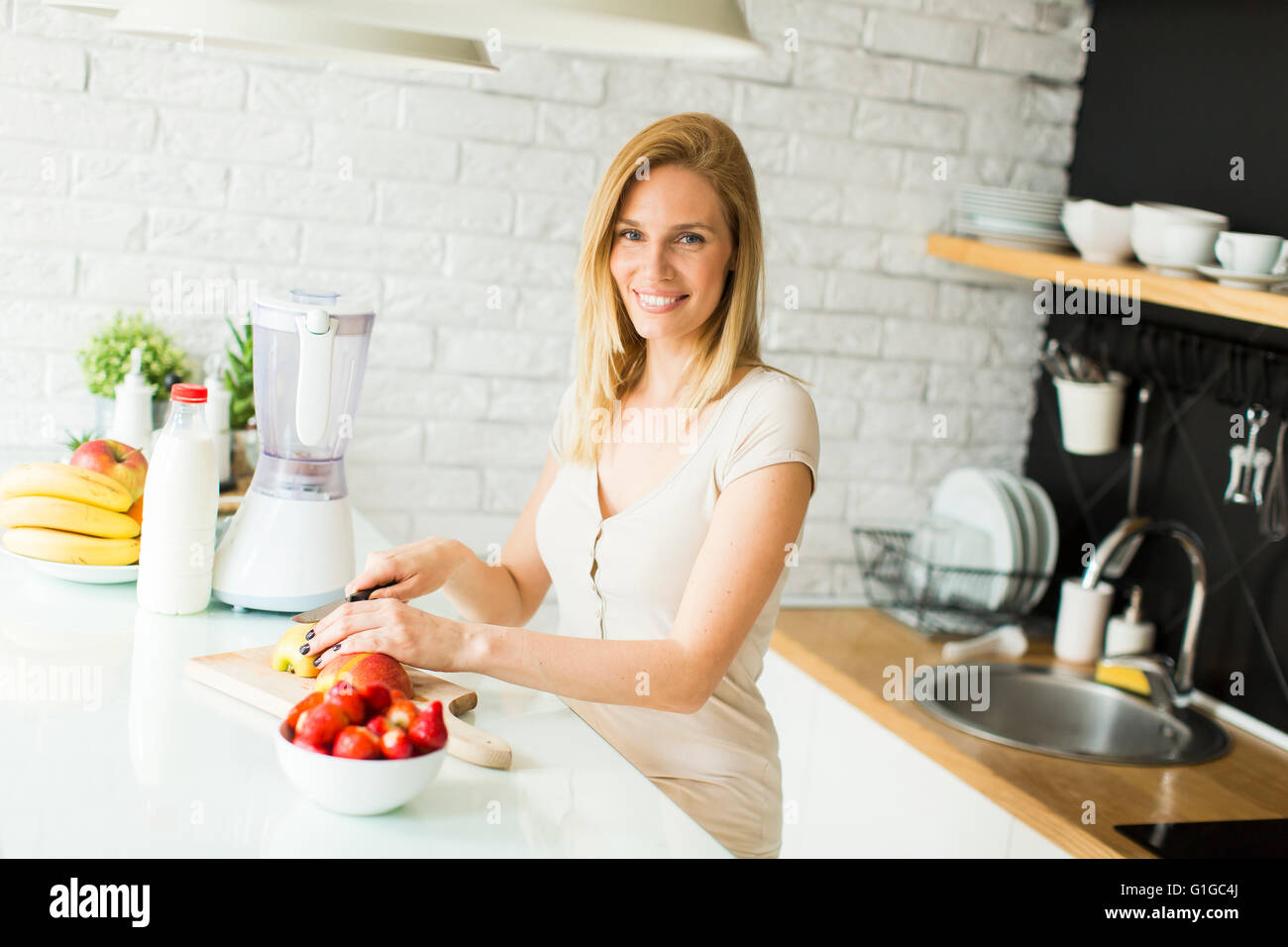 Jolie jeune femme la préparation des fruits dans la cuisine moderne Banque D'Images