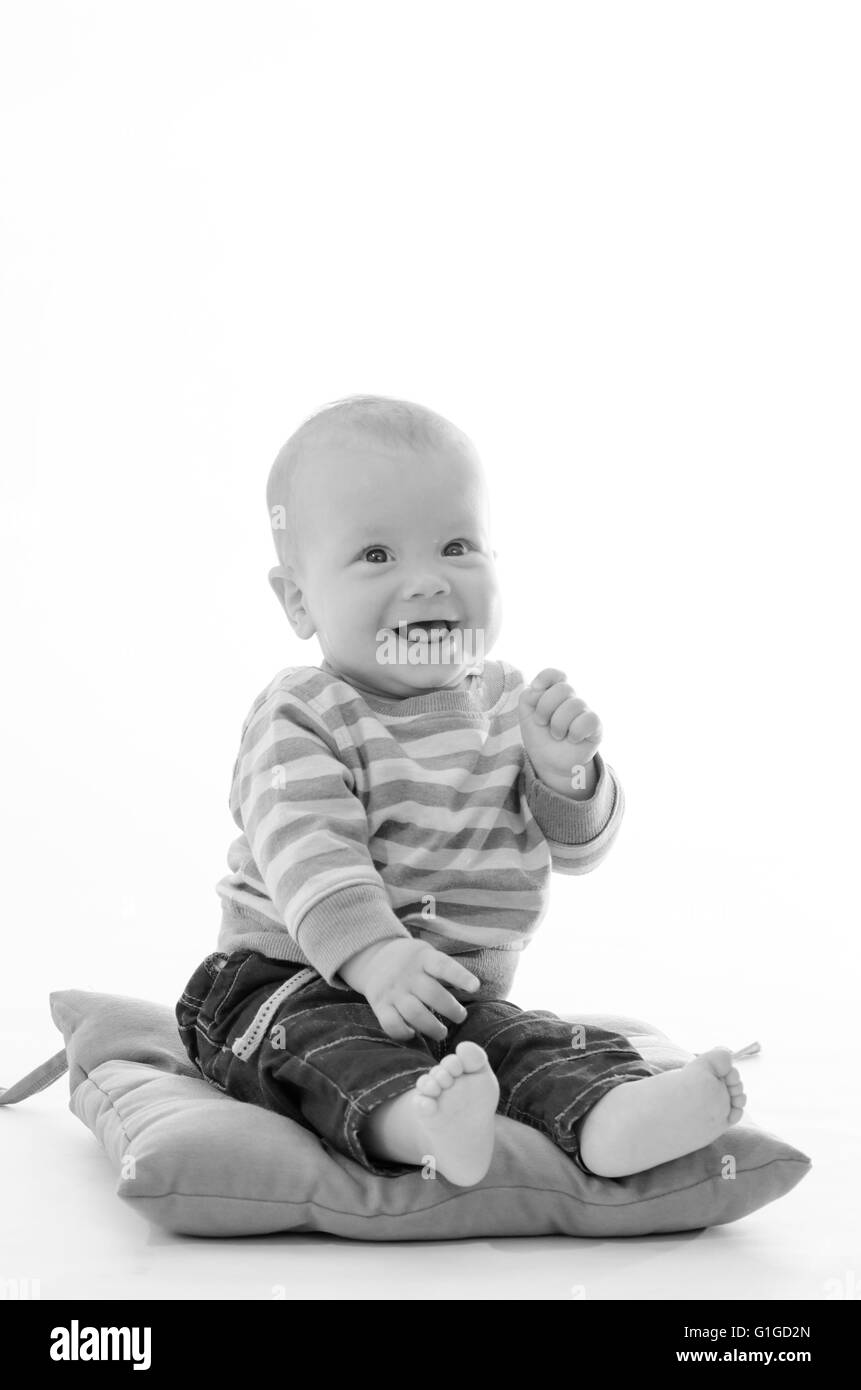 Sweet boy smiling infantile s'asseoir sur un oreiller vert isolated on white Banque D'Images