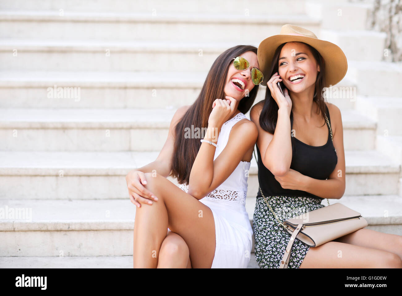 Deux jolies jeunes femmes à parler au téléphone mobile à jour d'été Banque D'Images