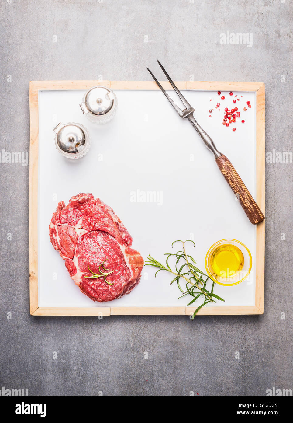 La viande de boeuf avec l'huile, les épices et la viande sur la fourchette de cuisine blanche sur fond gris bac en pierre, vue de dessus, cadre. Banque D'Images