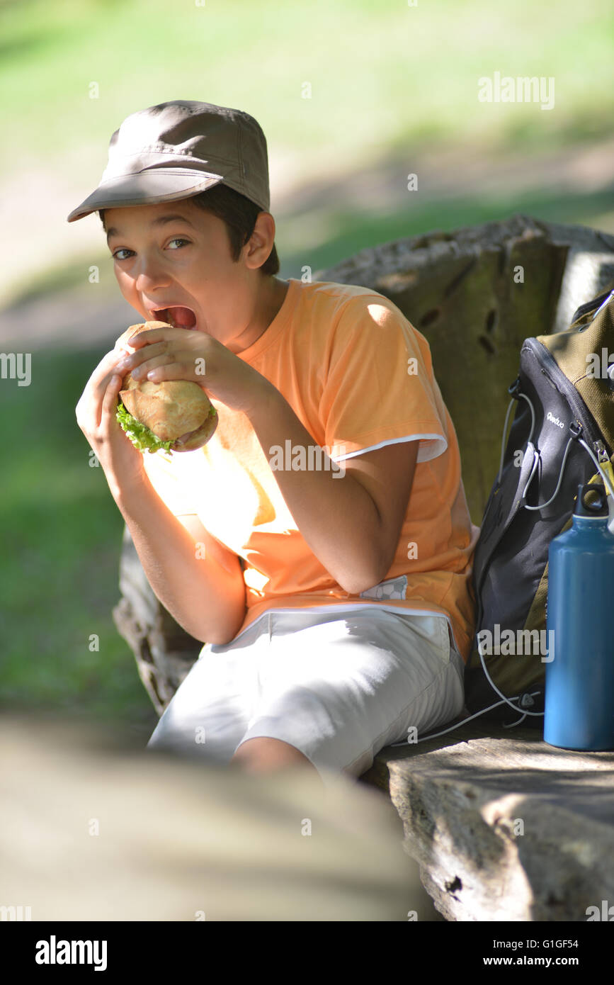 Jeune garçon en train de manger un sandwich après une promenade, France Banque D'Images