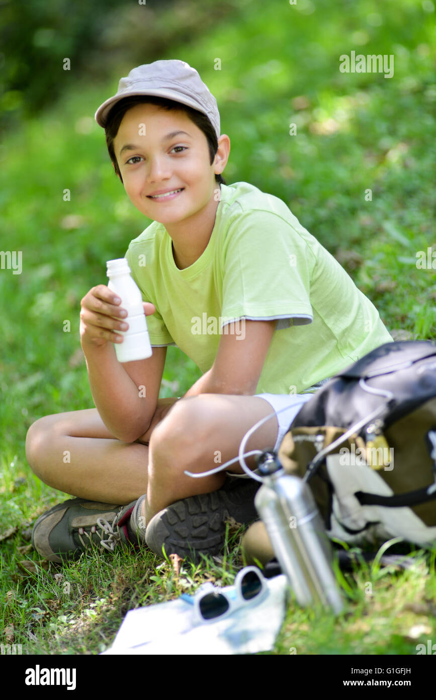 Jeune garçon assis dans l'herbe et de boire un verre de lait Banque D'Images