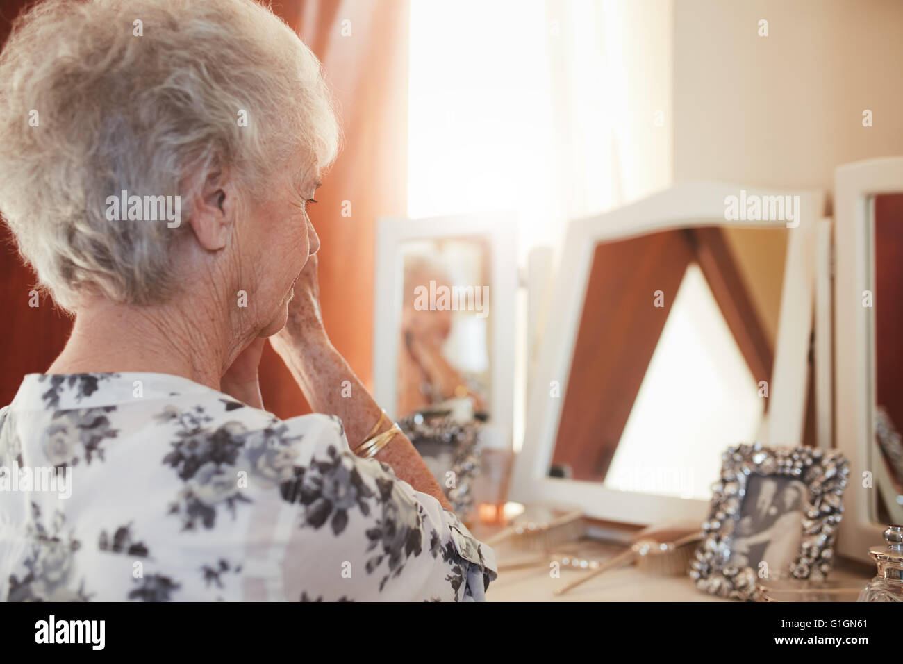 Close up shot of a senior woman prêt à dresser. Femme âgée assise à une commode dans la chambre. Banque D'Images