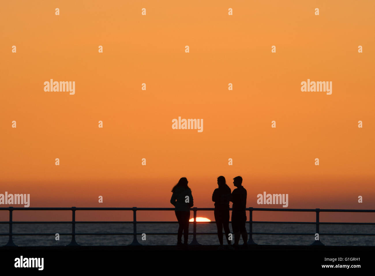 , Pays de Galles Aberystwyth UK, samedi 14 mai 2016 UK weather : un coucher de soleil spectaculaire à la fin de la journée d'un ciel dégagé et un soleil brillant, comme des gens marcher le long du port à Aberystwyth, sur la côte ouest de la Baie de Cardigan au Pays de Galles. Crédit photo : Keith Morris/Alamy Live News Banque D'Images