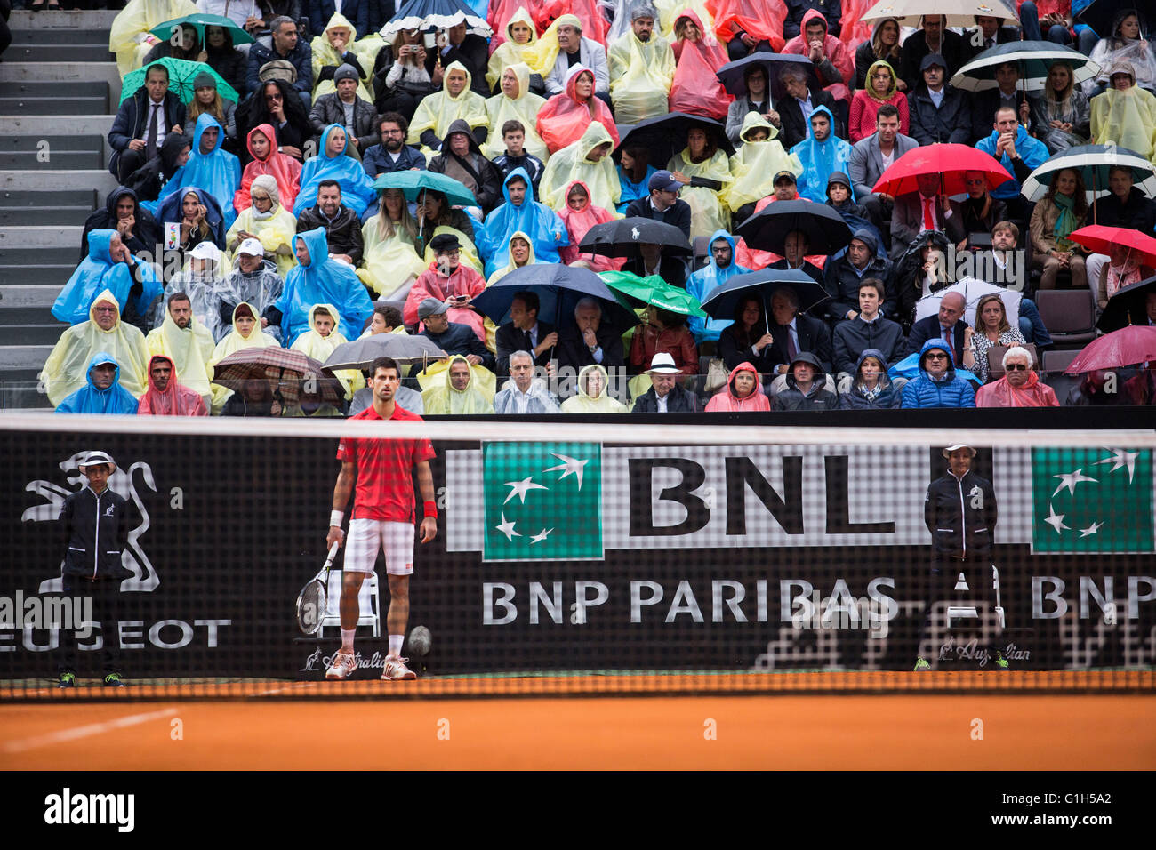 Faire foule parapluies et ponchos usure lors d'une douche dans la BNL Rome International finale entre Novak Djokovic et Andy Murray Banque D'Images