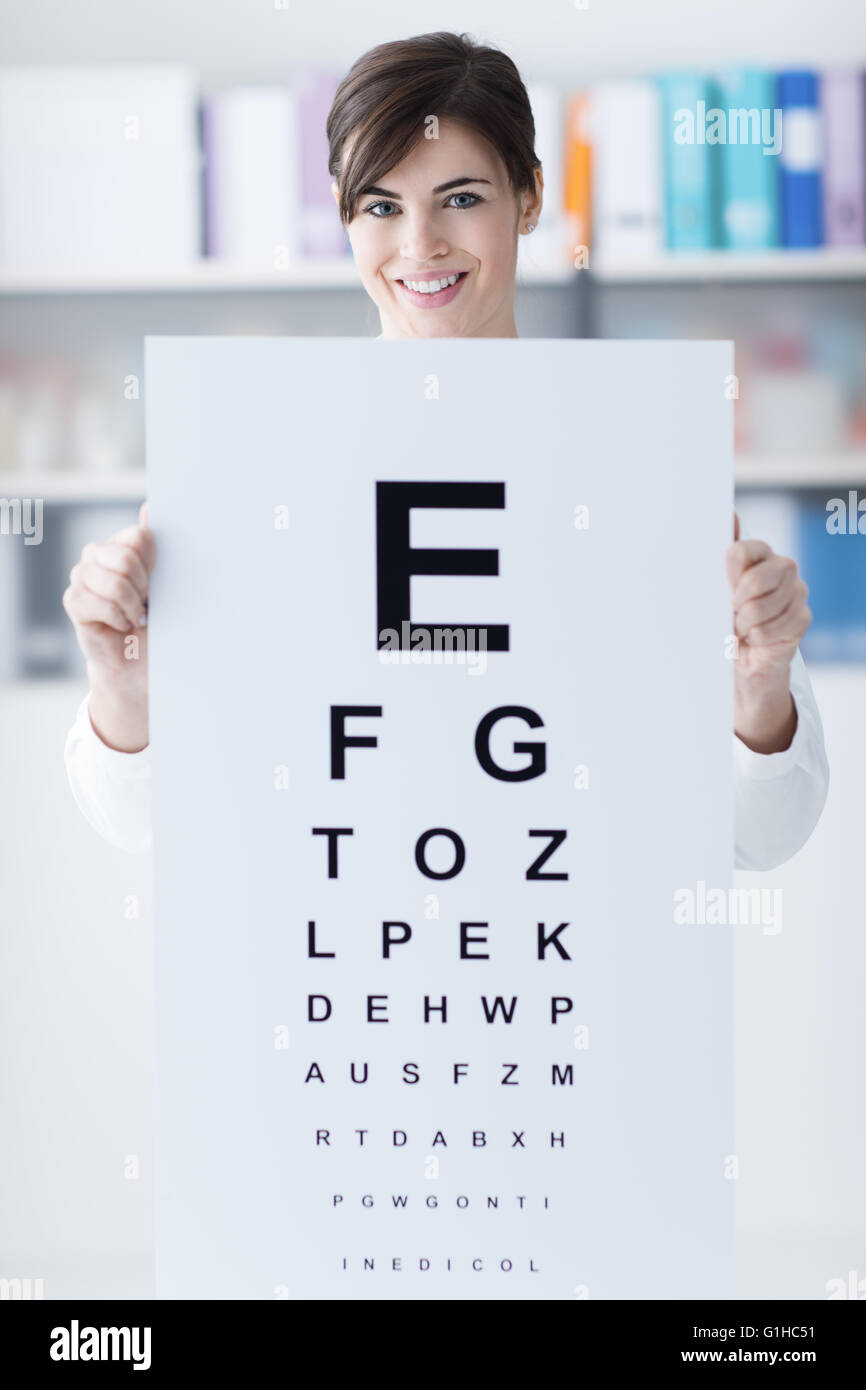 Professionnel des femmes titulaires d'un oculiste eye chart and smiling at camera, examen médical et soins de la vue concept Banque D'Images