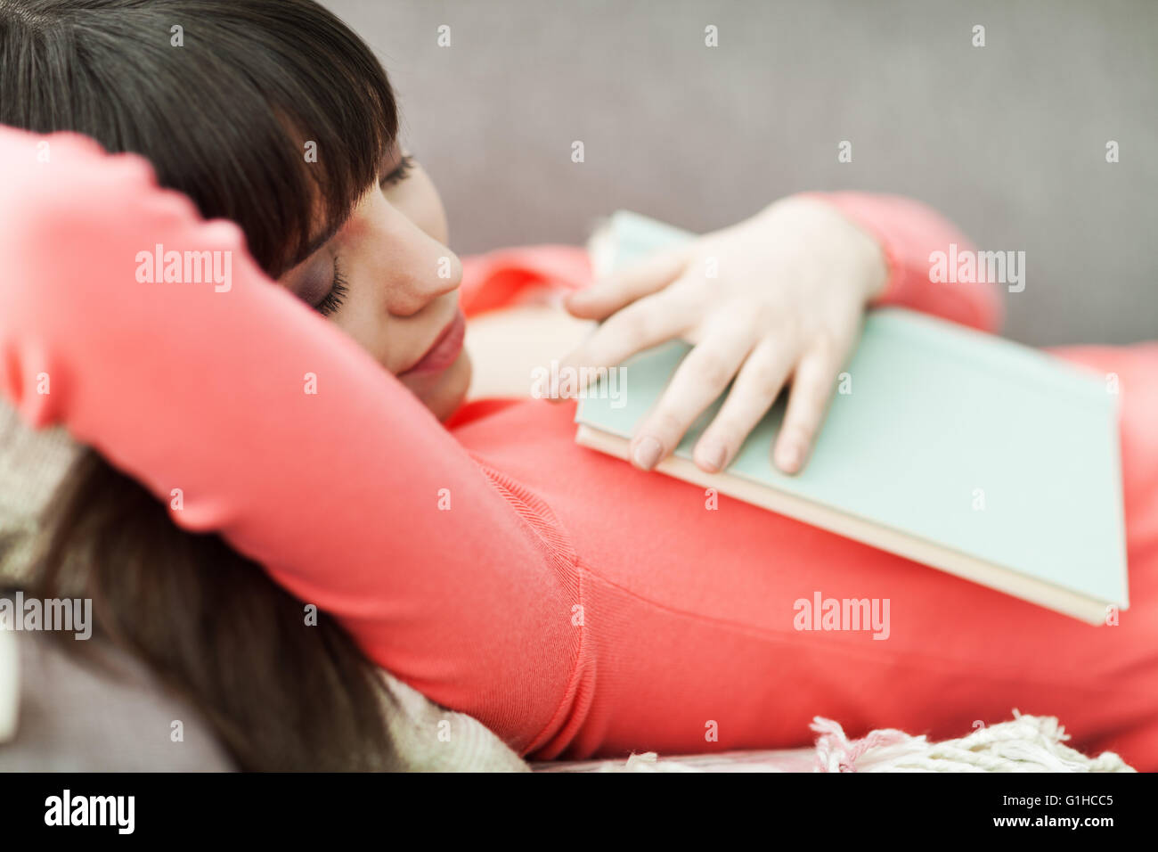 Jolie femme dormir sur le canapé avec les yeux fermés, elle lisait un livre Banque D'Images