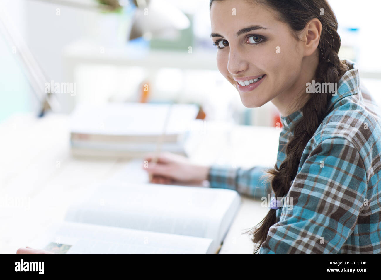 Souriante jeune fille étudiant l'étude et la lecture d'un livre, l'éducation et l'apprentissage concept Banque D'Images