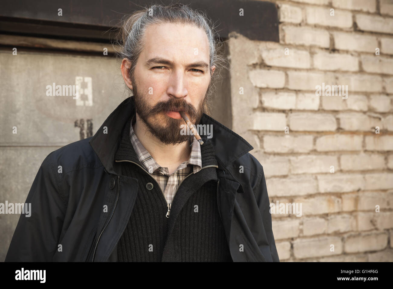 Homme barbu cigarette plus vieux mur de briques, outdoor portrait with selective focus Banque D'Images