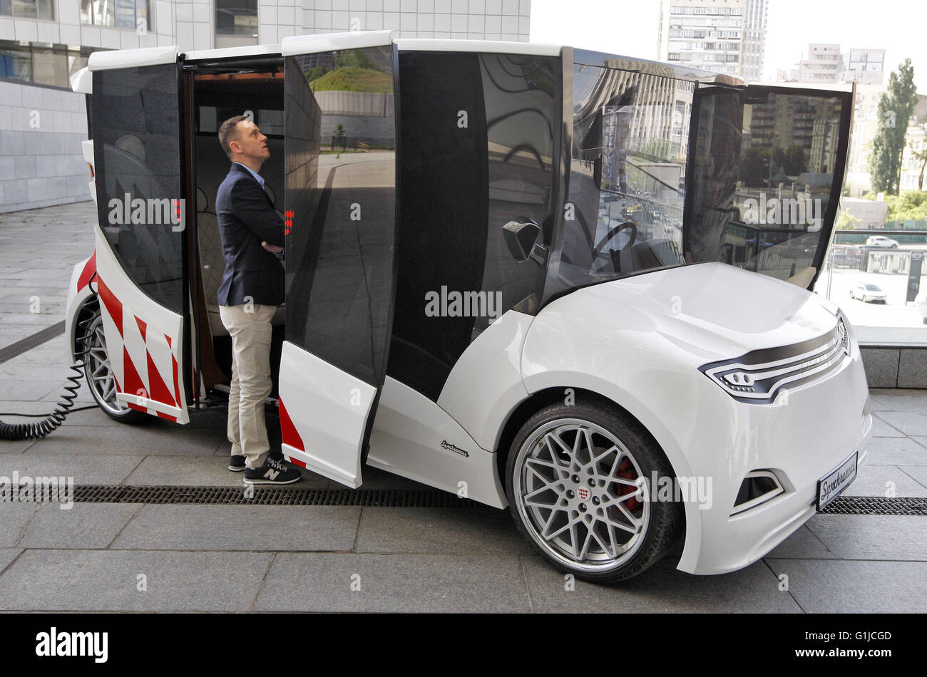 Kiev, Ukraine. 16 mai, 2016. Un homme d'oeil sur un prototype de voiture électrique premier Ukrainien 'Synchronous', au cours de présentation il à Kiev, Ukraine, le 16 mai, 2016. 'Synchronous" développé par entreprise ukrainienne Electric International Marathon est une voiture électrique avec moteur électrique innovant, panneaux solaires sur le toit, fenêtres panoramiques et l'extérieur qui me rappelle d'un chariot médiéval. La voiture en substance à l'utilisant comme une voiture de tourisme et de transport en taxi, et en mesure de surmonter la distance entre 130 et 160 kilomètres. © Vasyl Shevchenko/Pacific Press/Alamy Live News Banque D'Images