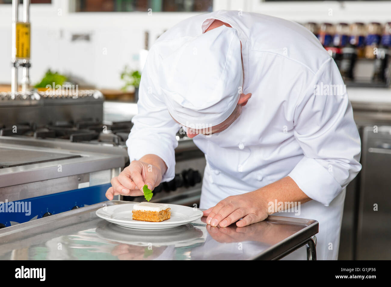 Chef professionnel décorer un dessert gâteau avec des feuilles de citron Banque D'Images