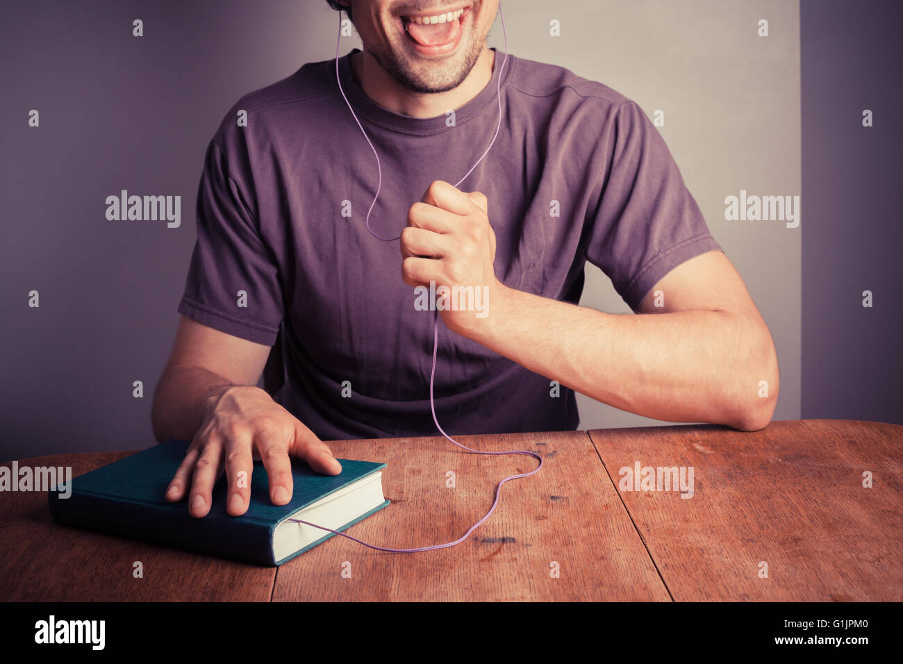 Un jeune homme est en train d'écouter un livre audio Banque D'Images