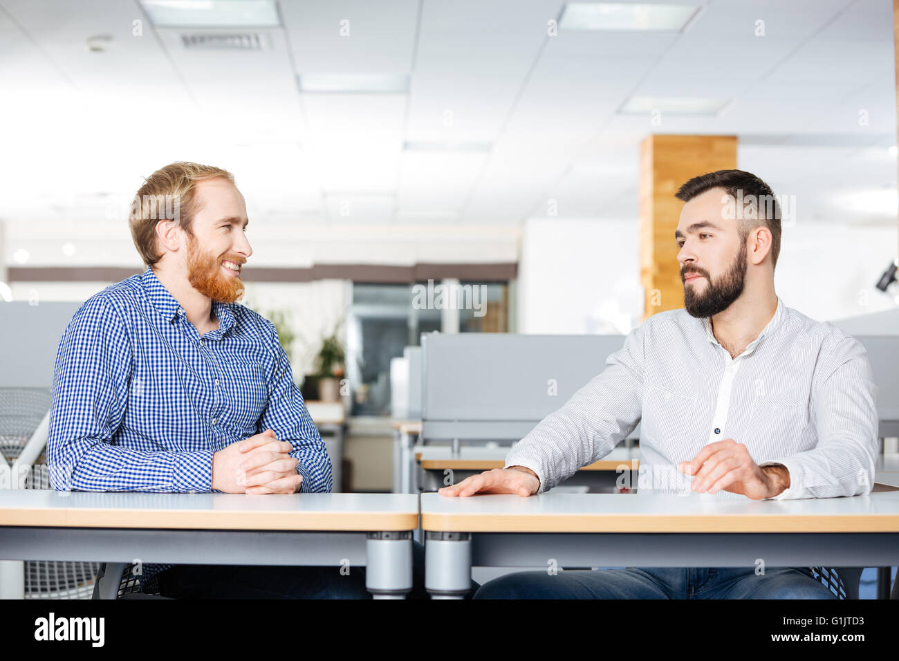 Deux hommes d'attrayants gaie et parler assis à la table in office Banque D'Images