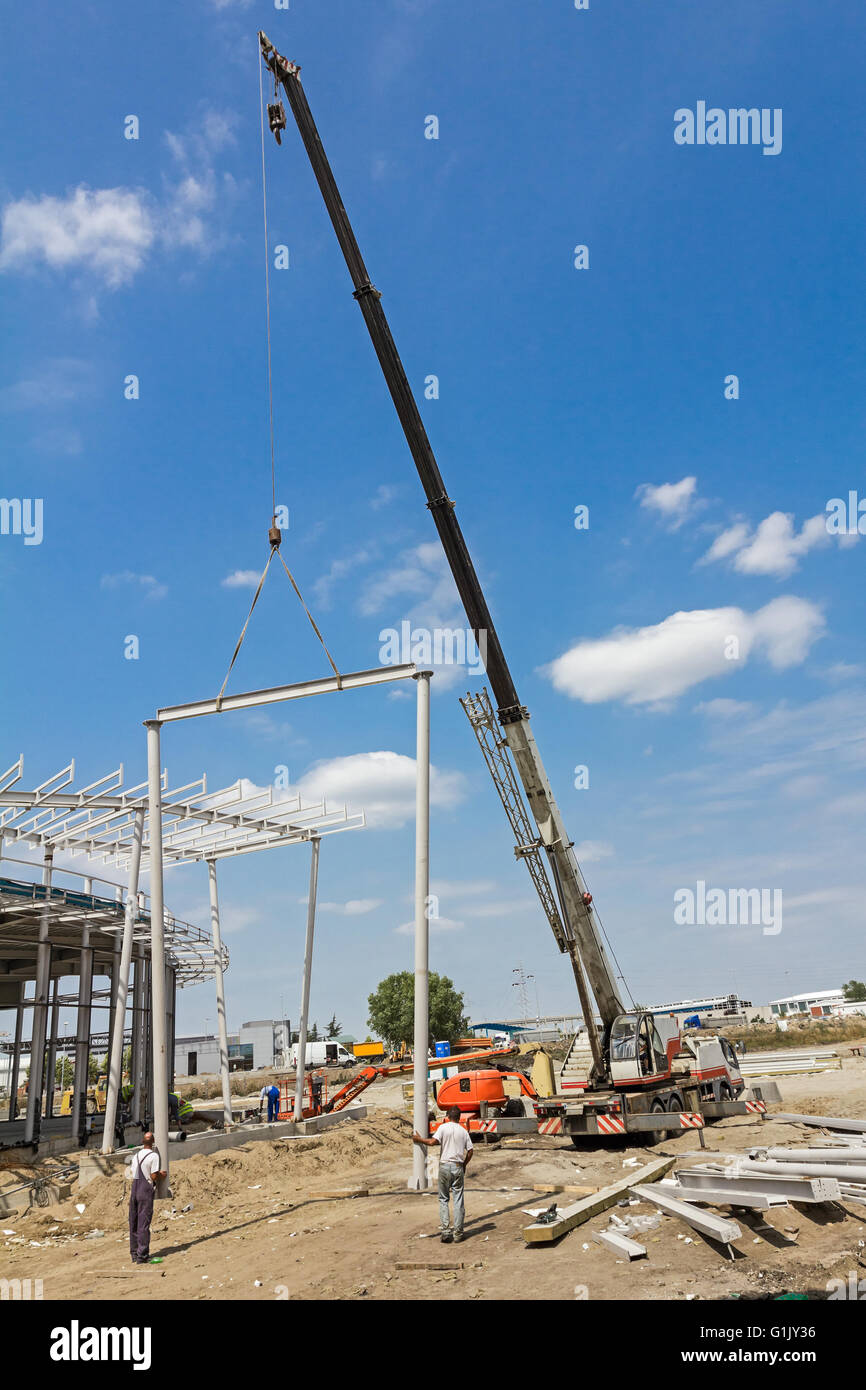 Grue mobile est transporter cadre métallique à l'assemblage. Les travailleurs sont d'aider sur le terrain. Banque D'Images