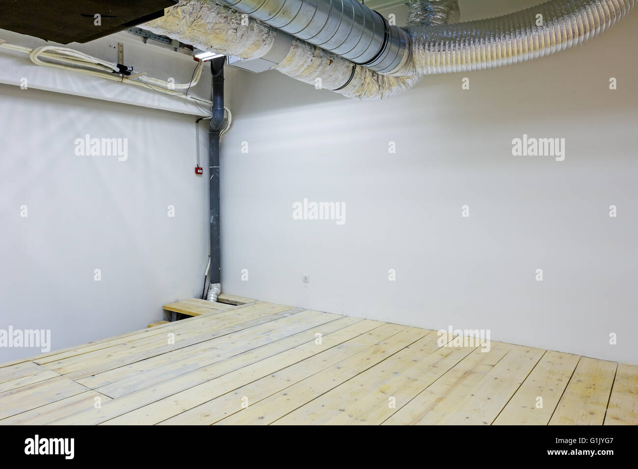 Les tuyaux de ventilation pour l'air conditionné sur le plafond dans une salle vide avec un plancher en bois. Banque D'Images