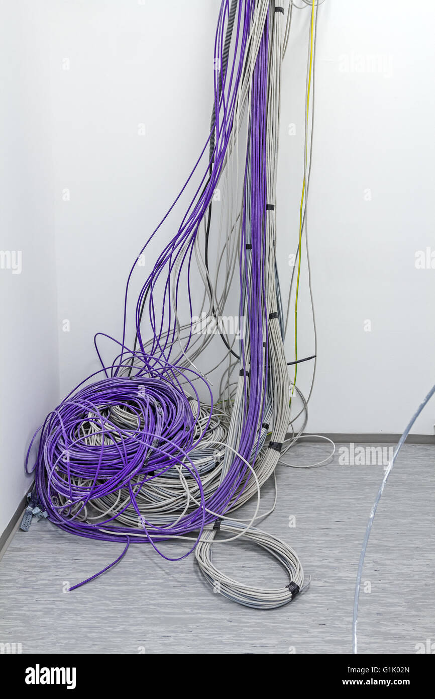 Un faisceau de câbles de communication sont suspendus au plafond dans la chambre. Banque D'Images