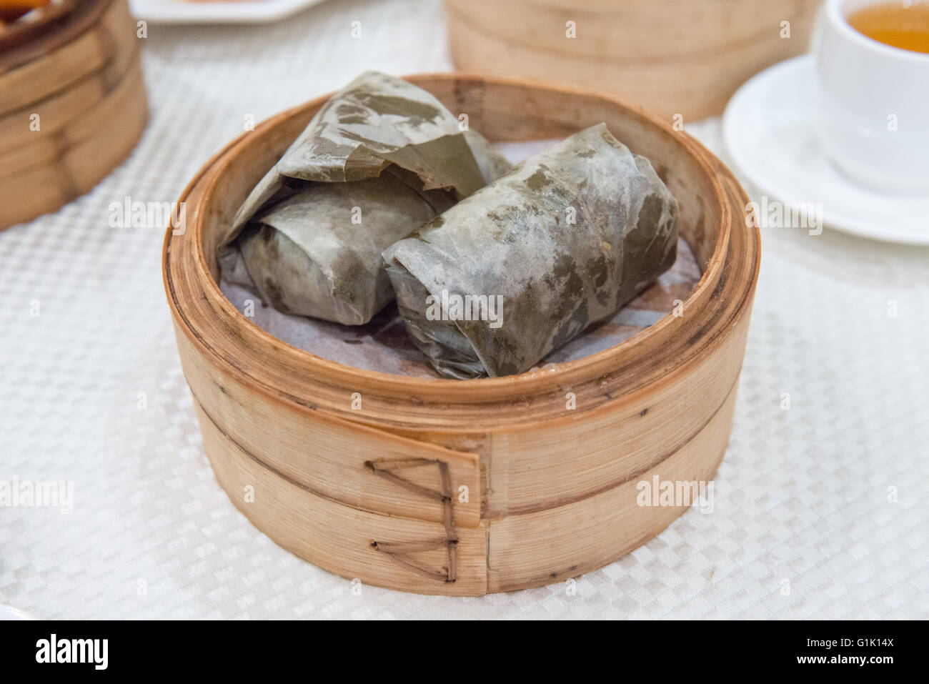 Enveloppé de feuilles la viande et les légumes dans le panier de bambou à dim sum Banque D'Images