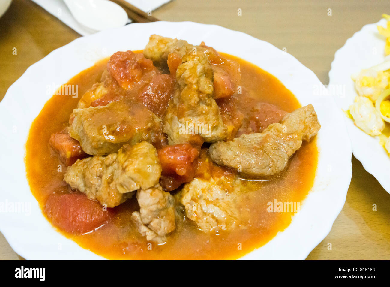 Ragoût de porc et les tomates dans un plat blanc Banque D'Images