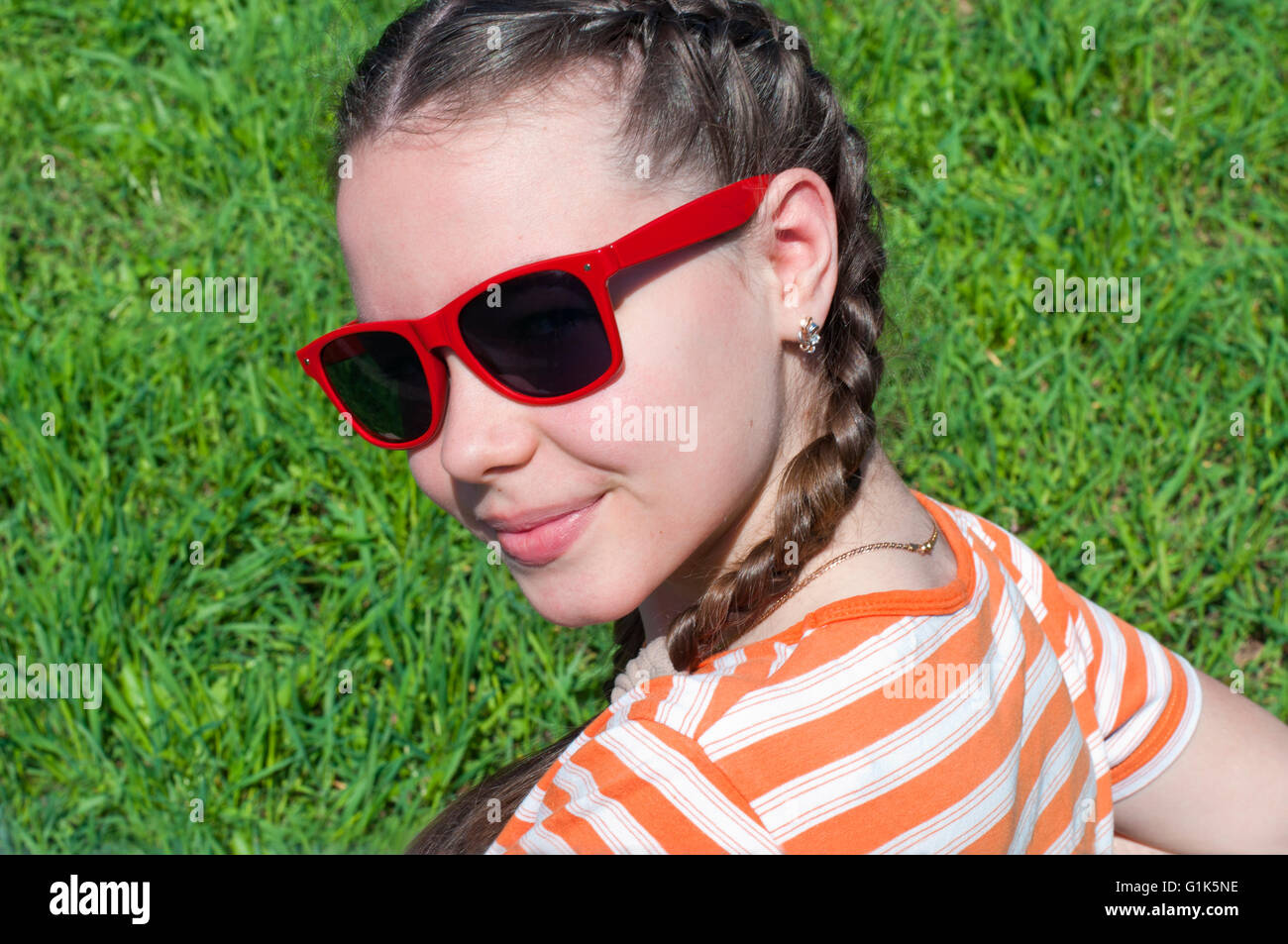 Fille avec des tresses assis sur une chaise se retourne et sourit Banque D'Images