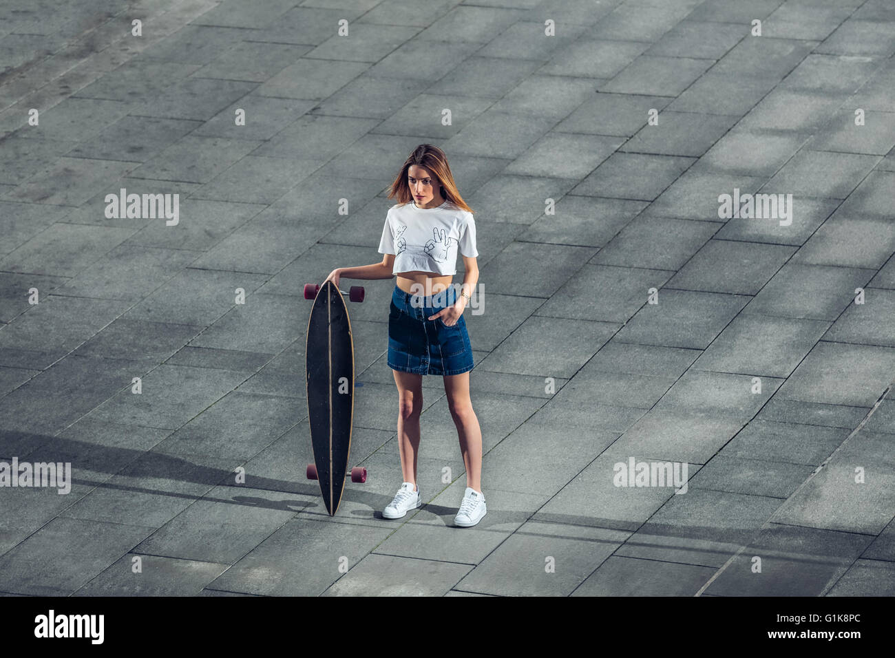 Belle femme debout avec longboard dans la ville Banque D'Images