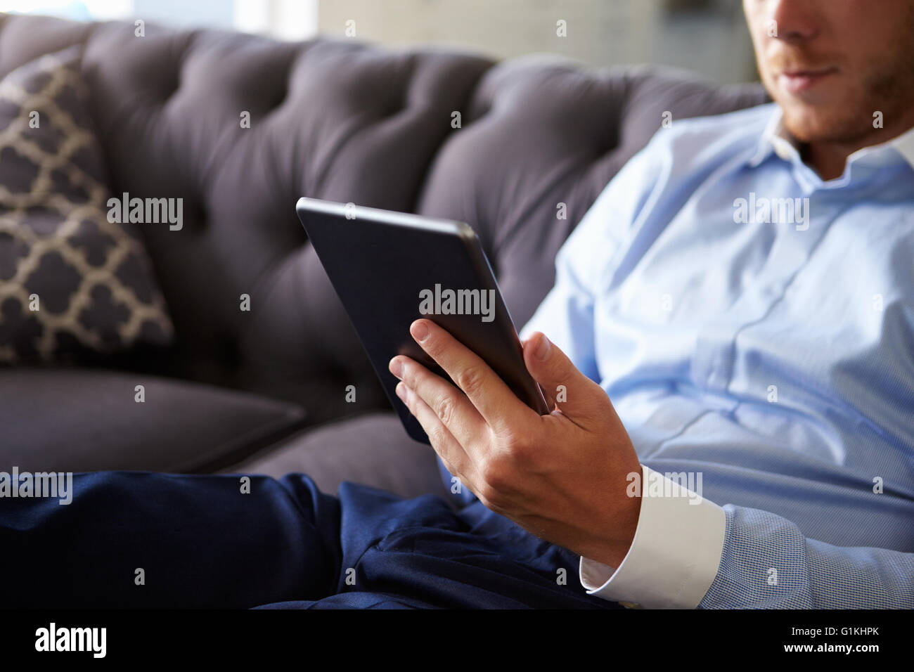 Close Up of Man Sitting on Sofa Using Digital Tablet Banque D'Images