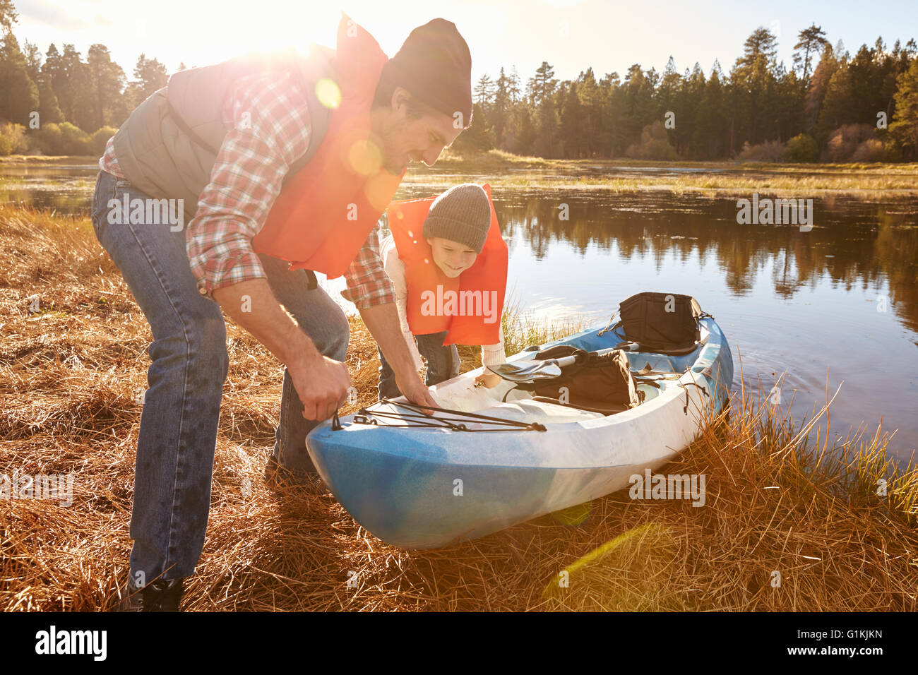 Père et fils la préparation de kayak pour lancer à partir de lakeside Banque D'Images