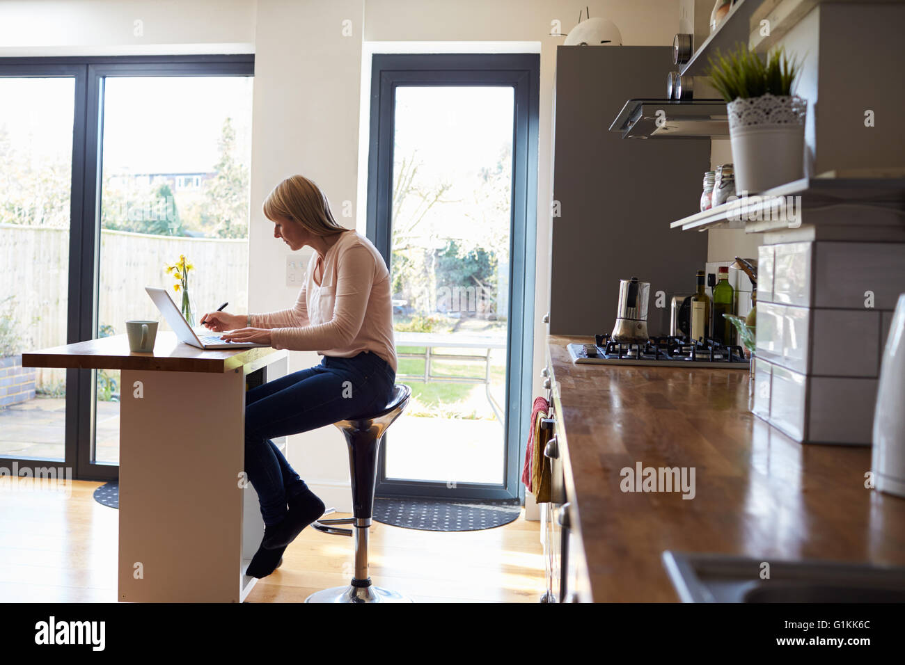 Femme Travail à domicile sur ordinateur portable en appartement moderne Banque D'Images