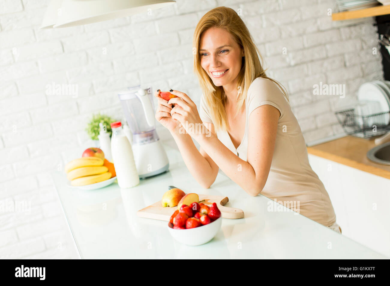 Jolie jeune femme la préparation des fruits dans la cuisine moderne Banque D'Images
