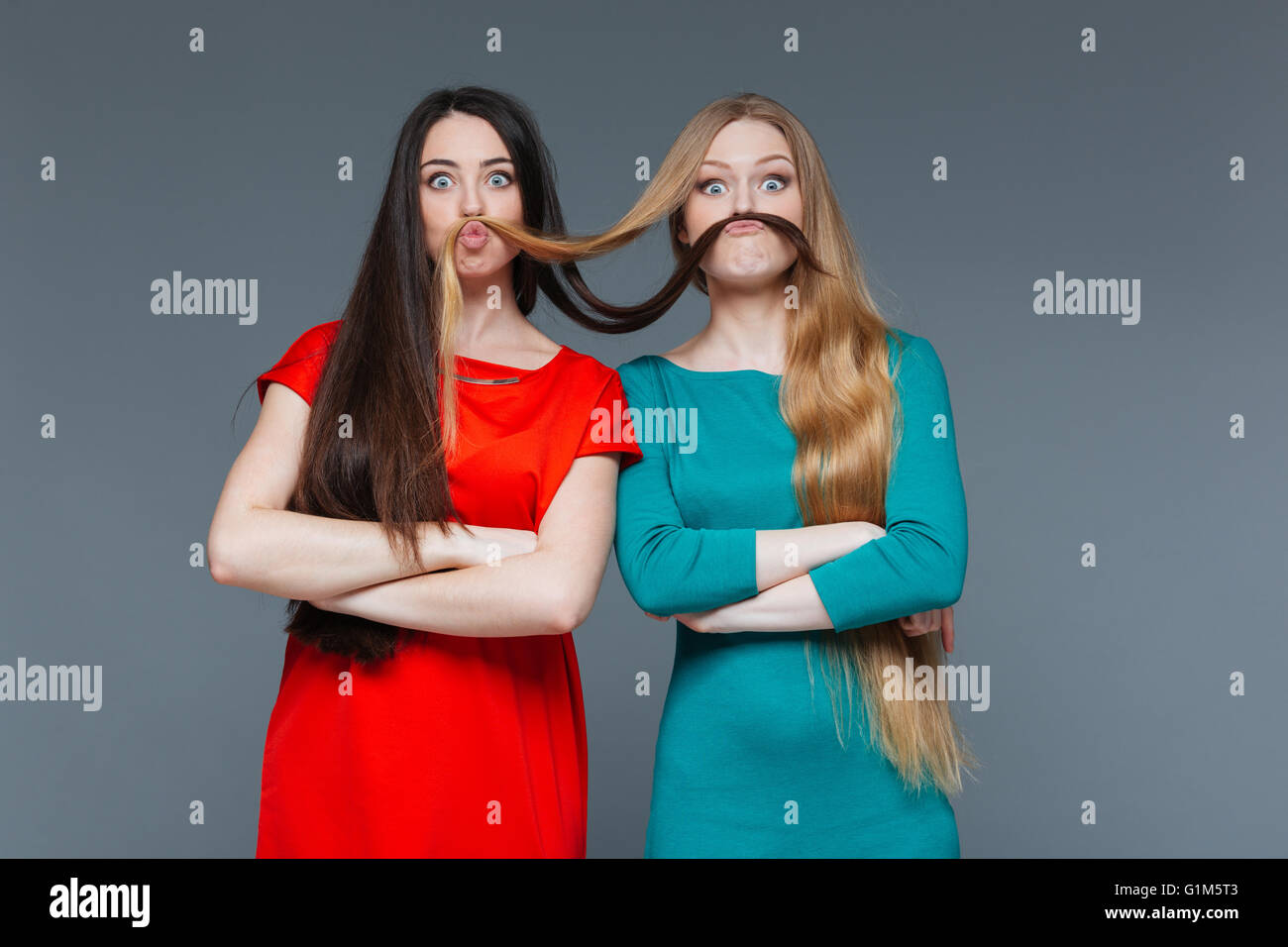 Funny Girls deux décisions moustache avec leurs cheveux sur fond gris Banque D'Images