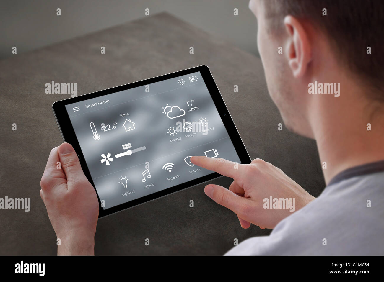 Utiliser l'homme pour l'application smart home control sur tablette. Intérieur de salle de séjour dans l'arrière-plan. Banque D'Images