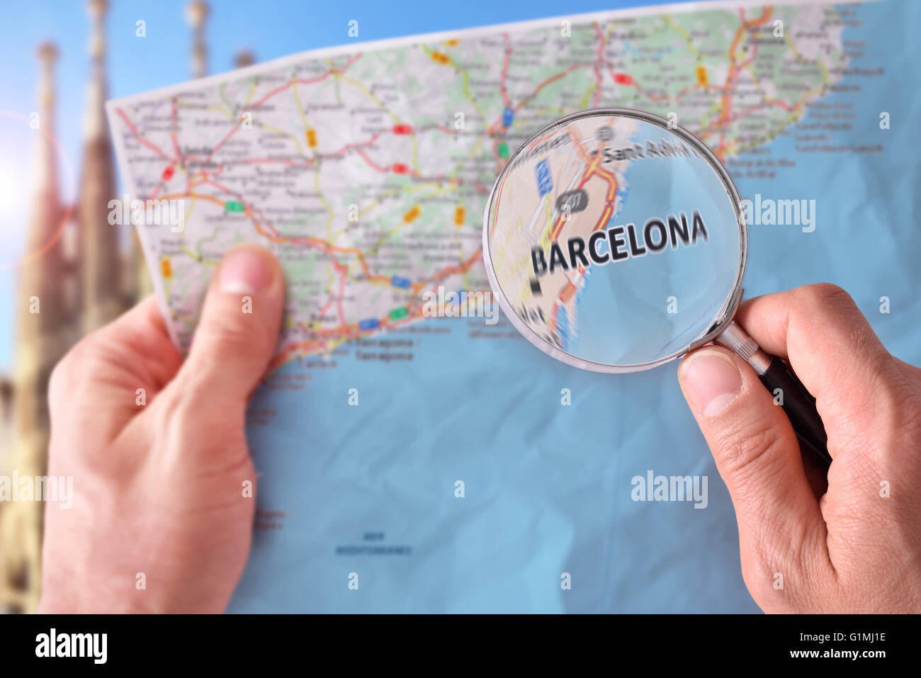 Mains de ramasser une carte de Barcelone et à la recherche d'un endroit à l'aide d'une loupe avec un représentant dans le monument backg Banque D'Images