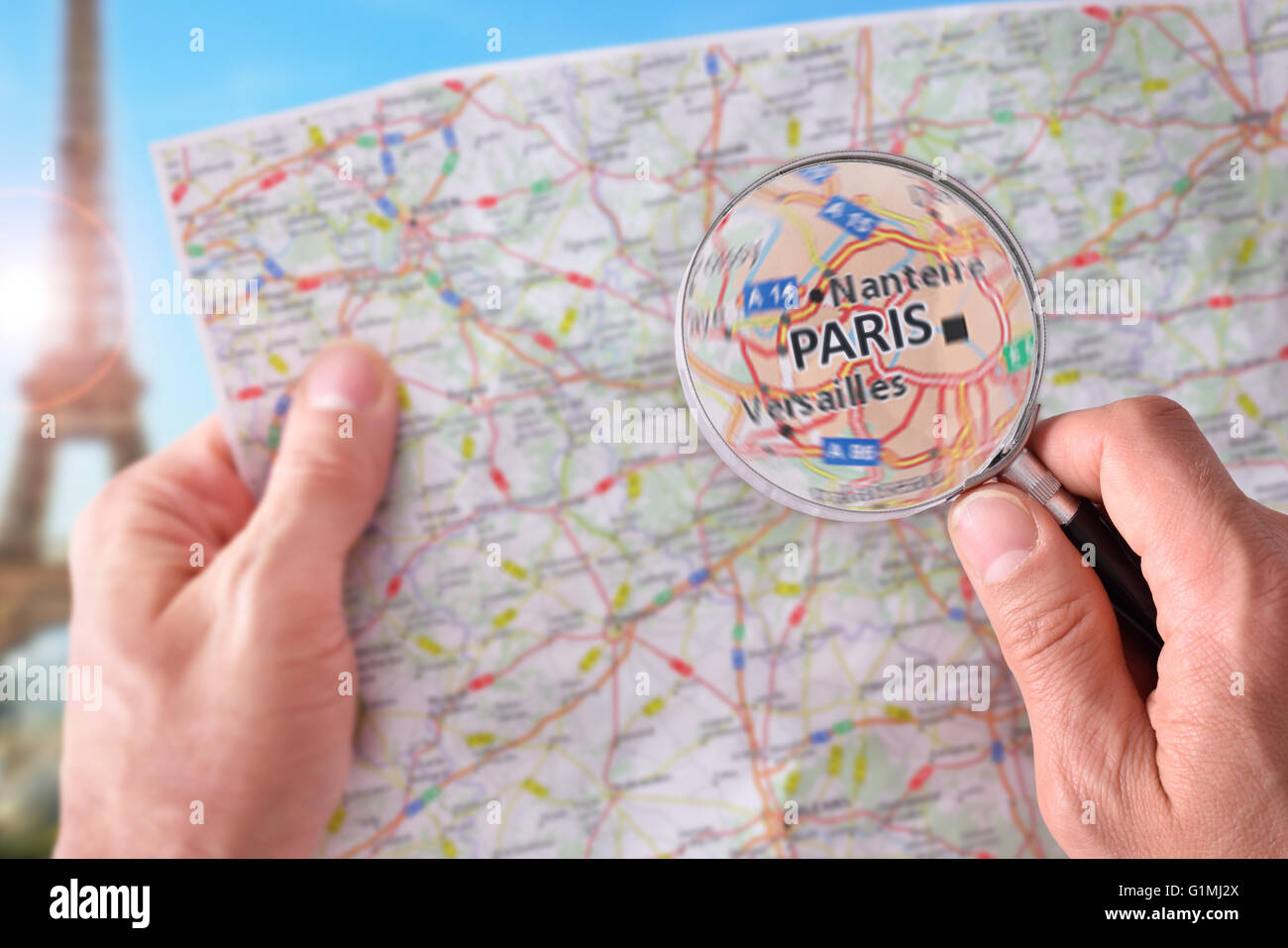 Mains de prendre un plan de Paris et à la recherche d'un endroit à l'aide d'une loupe avec un représentant dans le monument backgroun Banque D'Images